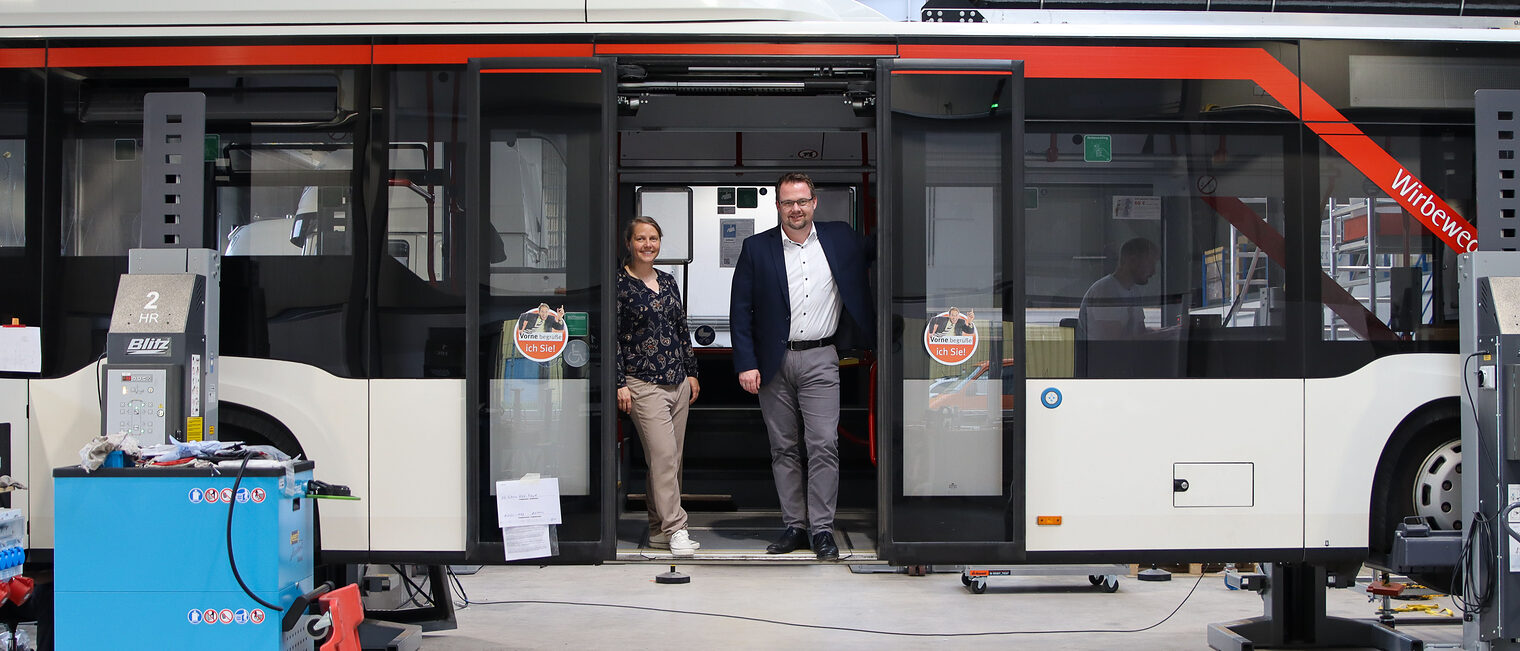 Die Geschäftsführer Leonie Behrens und Philip Wagemann stehen in einem Linienbus, der auf Wasserstoff umgerüstet wird. 