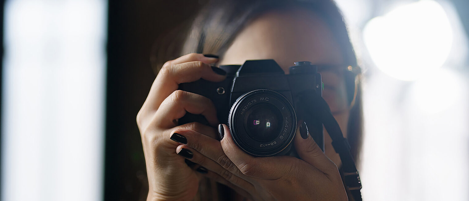 Frau mit dunklem Nagellack fotografiert mit Spiegelreflexkamera im Gegenlicht