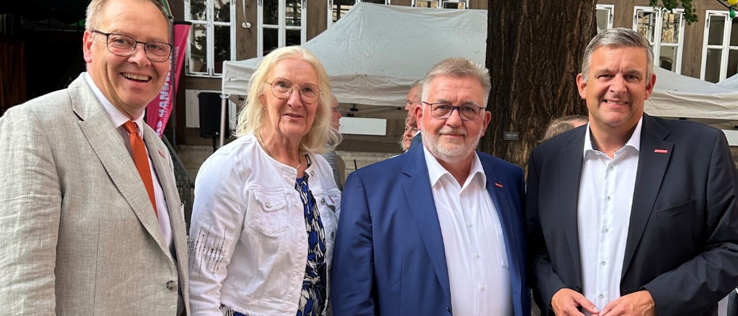 Austausch bei einer Veranstaltung des Handwerks in historischem Ambiente Gruppenfoto mit vier Personen im Anzug bei Veranstaltung im Freien vor Fachwerk-Kulisse und Ginkgobaum