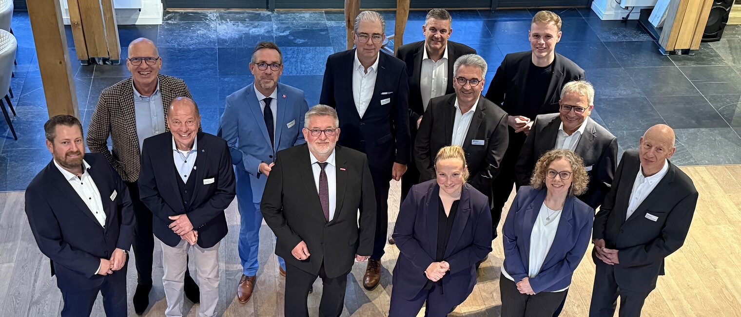 Austausch beim Parlamentarischen Abend der Wirtschaft 2025  Gruppenfoto von Teilnehmer:innen des Parlamentarischen Abends der Wirtschaft 2025 in Businesskleidung vor moderner Kulisse